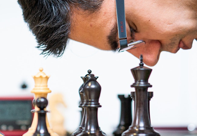 chess piece in black and white and face of a man wearing glasses and dark hair